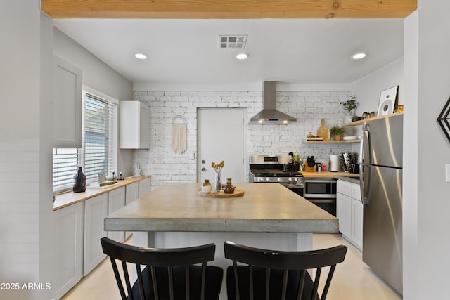 kitchen with wall chimney range hood, backsplash, a breakfast bar area, and stainless steel appliances