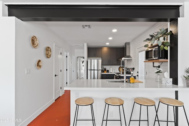 kitchen featuring tasteful backsplash, wall chimney exhaust hood, stainless steel fridge, and kitchen peninsula