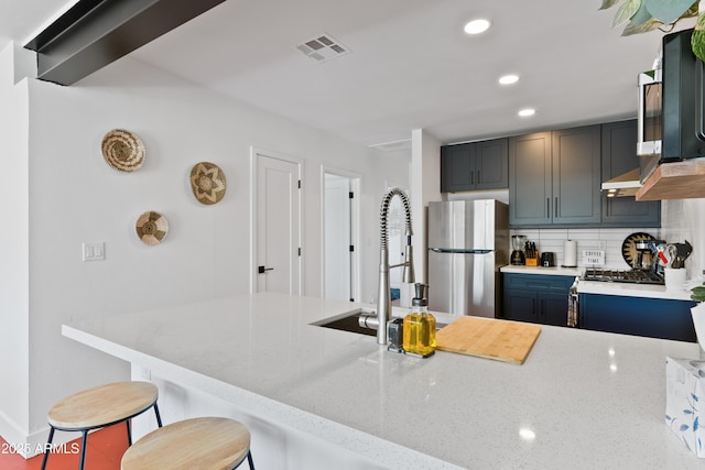 kitchen featuring stainless steel fridge, a kitchen breakfast bar, light stone counters, decorative backsplash, and kitchen peninsula