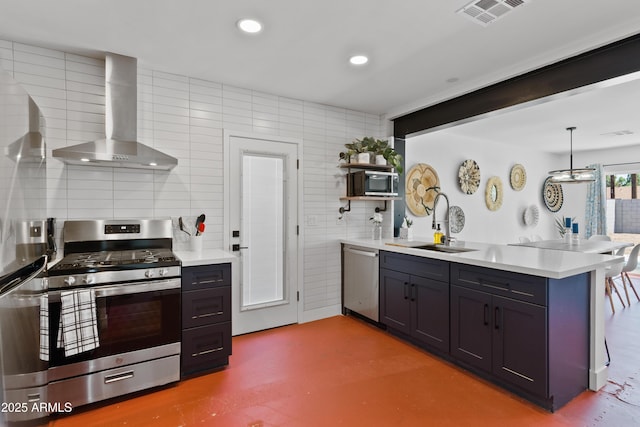 kitchen with decorative backsplash, hanging light fixtures, kitchen peninsula, stainless steel appliances, and wall chimney range hood