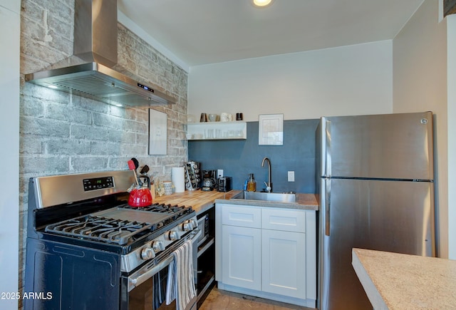 kitchen with butcher block countertops, sink, white cabinets, exhaust hood, and stainless steel appliances