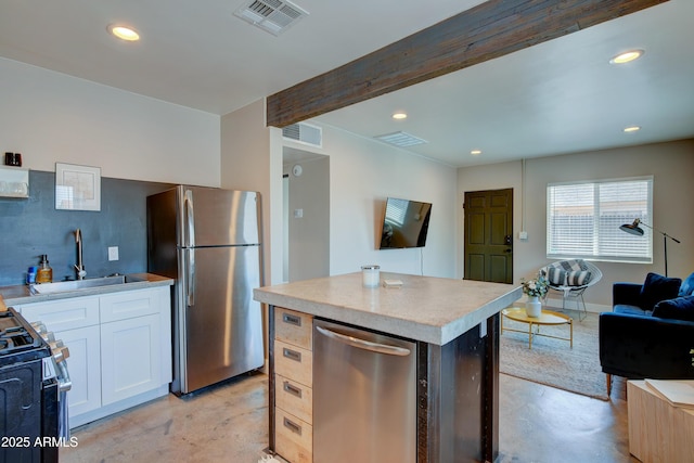 kitchen with beamed ceiling, white cabinetry, sink, a center island, and stainless steel appliances