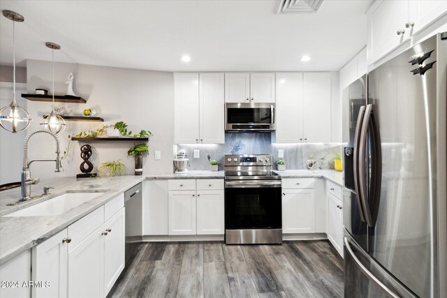 kitchen featuring white cabinets, appliances with stainless steel finishes, pendant lighting, and sink