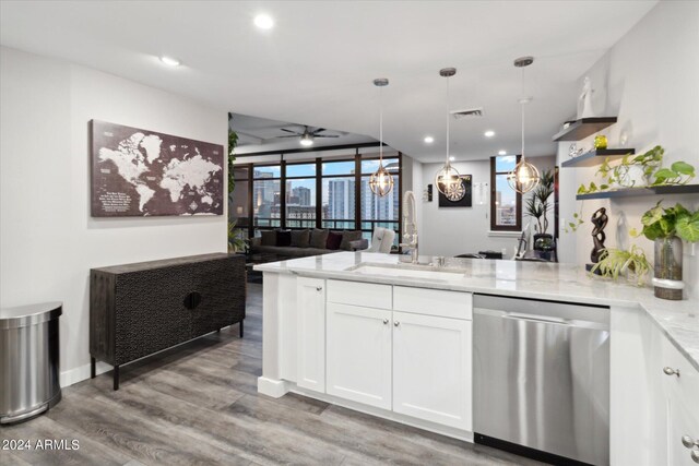 kitchen featuring light stone counters, stainless steel dishwasher, sink, decorative light fixtures, and white cabinetry