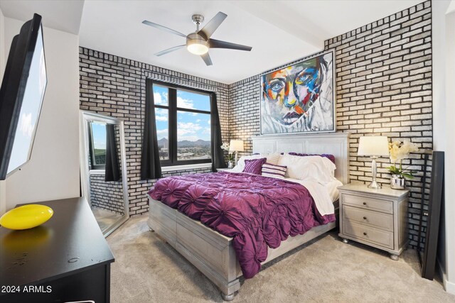 bedroom featuring ceiling fan, light colored carpet, and brick wall