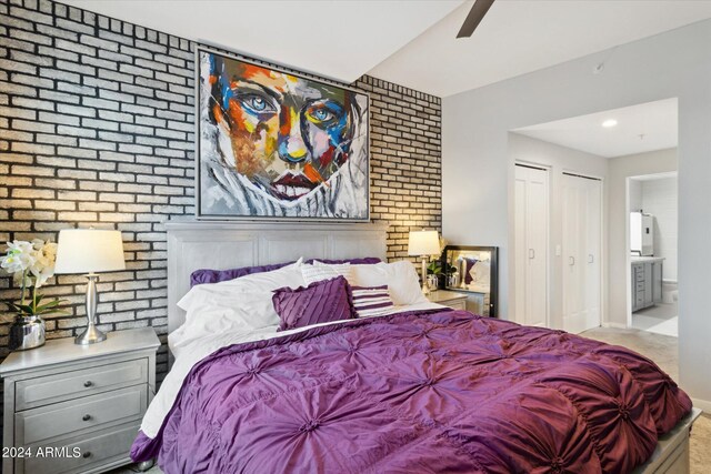 bedroom with connected bathroom, ceiling fan, and brick wall