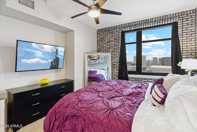 bedroom featuring ceiling fan and brick wall