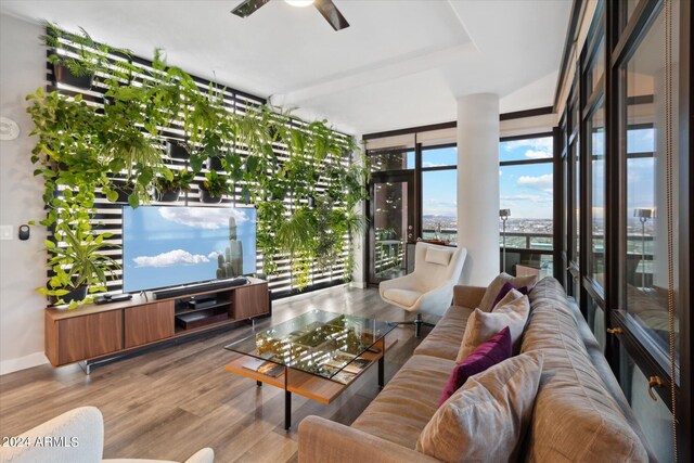 living room featuring ceiling fan, light hardwood / wood-style floors, and a wall of windows