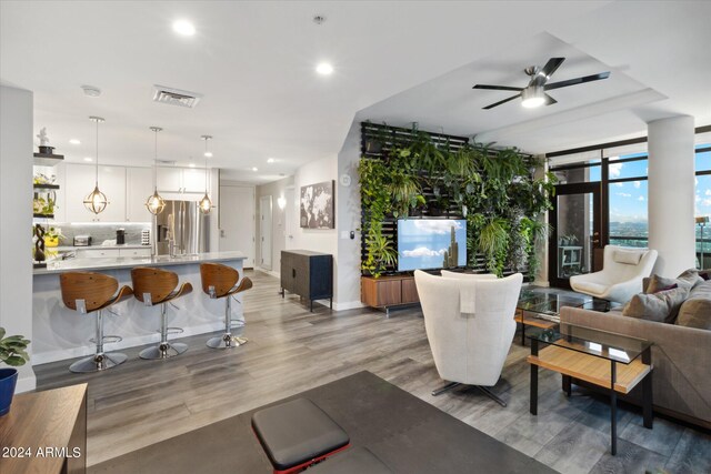 living room with light hardwood / wood-style floors, expansive windows, and ceiling fan