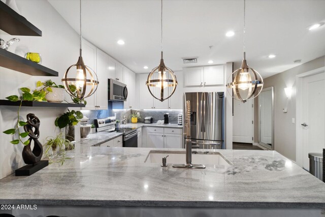 kitchen with light stone countertops, decorative backsplash, white cabinetry, and stainless steel appliances