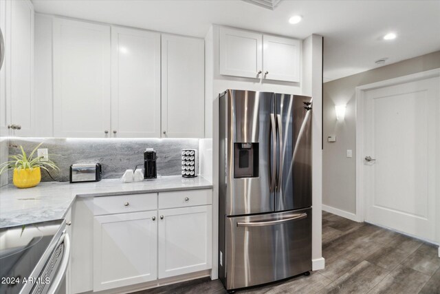 kitchen with dark hardwood / wood-style floors, stainless steel fridge, light stone countertops, and white cabinetry