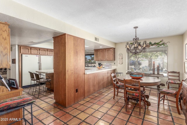 dining space with a notable chandelier, light tile patterned floors, and a textured ceiling