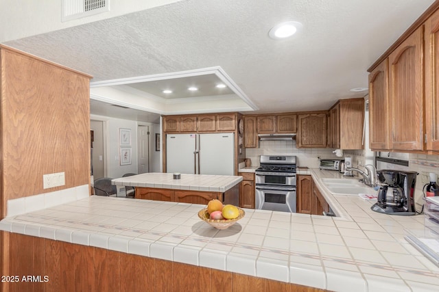 kitchen with range with two ovens, tile counters, and kitchen peninsula