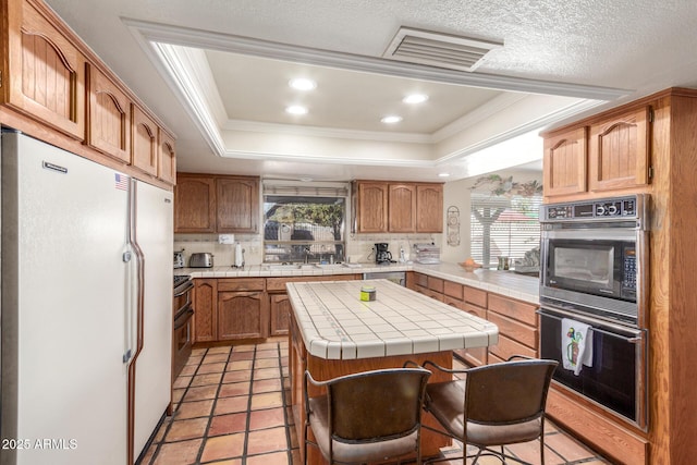 kitchen with a wealth of natural light, a center island, a raised ceiling, and white fridge