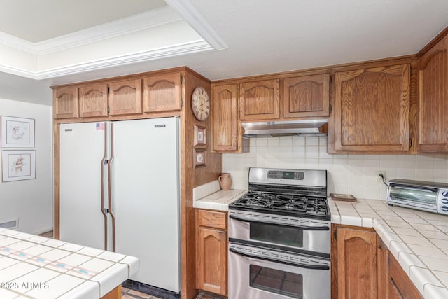 kitchen with white refrigerator, double oven range, tile counters, and tasteful backsplash