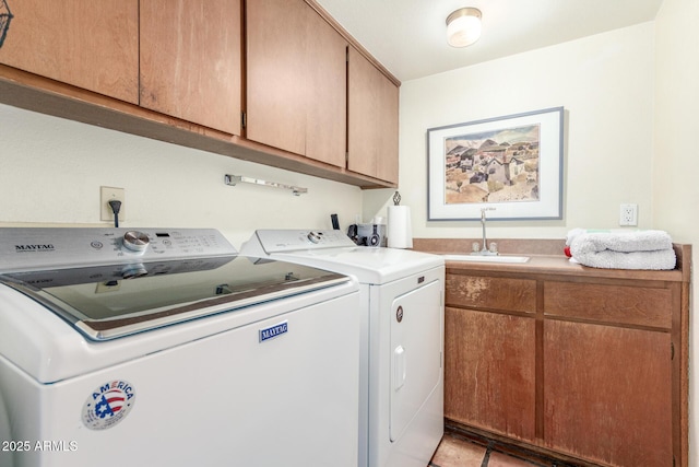 clothes washing area featuring sink, washer and clothes dryer, and cabinets