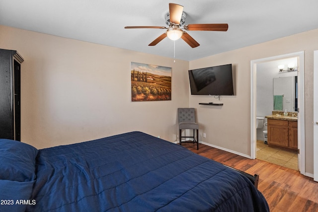 bedroom with light wood-type flooring, ensuite bathroom, ceiling fan, and sink