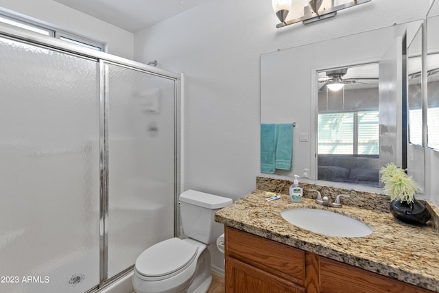 bathroom featuring ceiling fan, vanity, a shower with shower door, and toilet