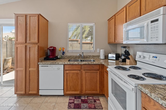 kitchen with light stone countertops, sink, light tile patterned flooring, and white appliances