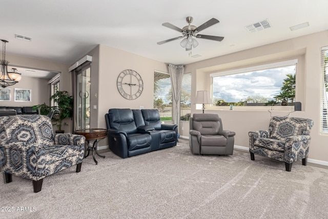 carpeted living room featuring ceiling fan with notable chandelier