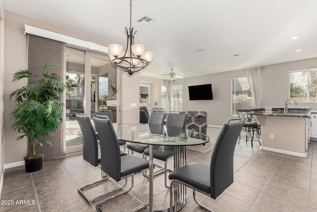 tiled dining room featuring sink and ceiling fan with notable chandelier