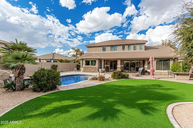 rear view of house with a fenced in pool, a patio area, and a lawn