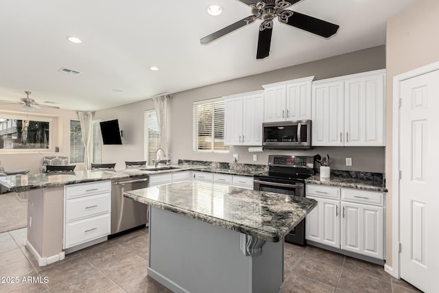 kitchen with stainless steel appliances, white cabinetry, a center island, and a breakfast bar