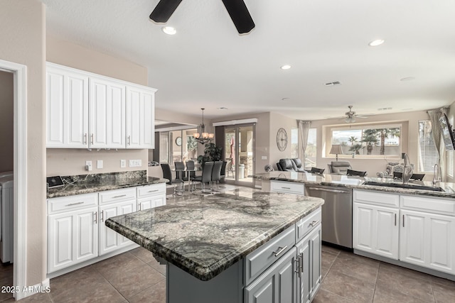 kitchen with white cabinetry, dark stone counters, dishwasher, and a kitchen island