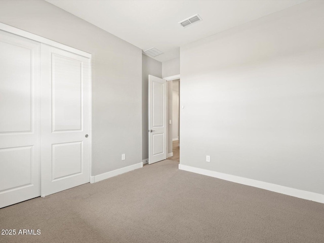 unfurnished bedroom with light carpet and a closet