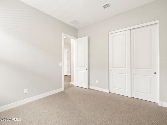 unfurnished bedroom with light carpet and a closet