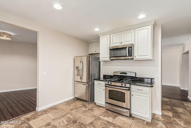 2807 N 8th Ave, Phoenix, AZ 85007 - kitchen with appliances with stainless steel finishes, dark countertops, baseboards, light stone finish floors, and white cabinetry