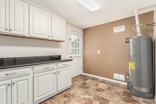 2807 N 8th Ave, Phoenix, AZ 85007 - washroom featuring gas water heater, baseboards, light stone finish floors, and cabinet space