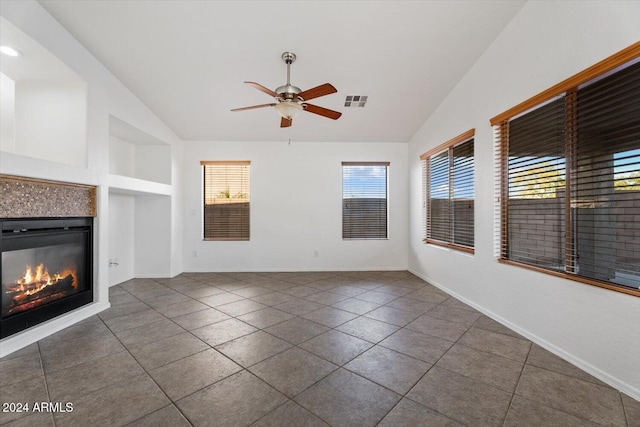 unfurnished living room featuring ceiling fan, dark tile patterned floors, built in features, lofted ceiling, and a fireplace