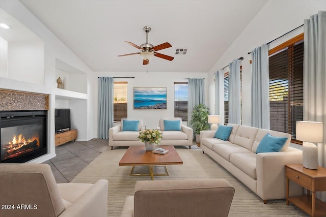 tiled living room featuring built in shelves, ceiling fan, and vaulted ceiling