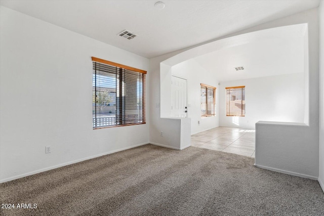 carpeted spare room featuring a healthy amount of sunlight and lofted ceiling