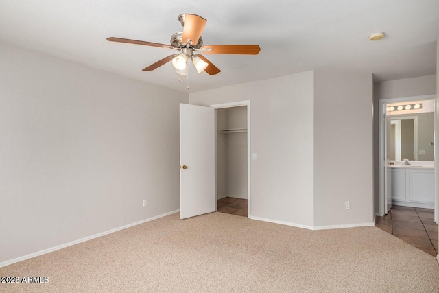 unfurnished bedroom with ceiling fan, a closet, connected bathroom, and carpet flooring