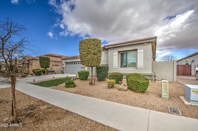 view of front of home with an attached garage, fence, a tile roof, driveway, and stucco siding