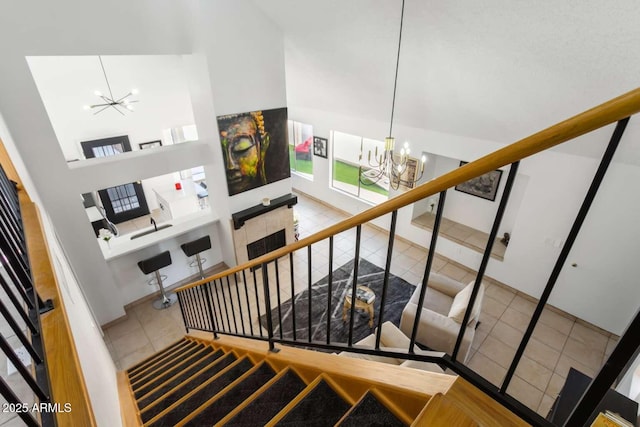 stairway featuring a chandelier, a towering ceiling, and tile patterned floors