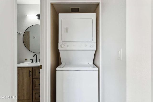 washroom featuring stacked washer and dryer and a sink