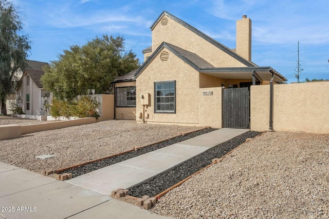 view of front of property featuring a chimney, fence private yard, a gate, and stucco siding