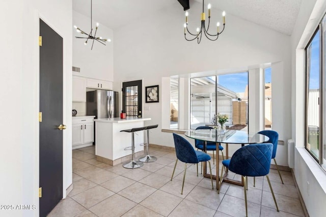 dining room featuring a healthy amount of sunlight, an inviting chandelier, light tile patterned floors, and vaulted ceiling