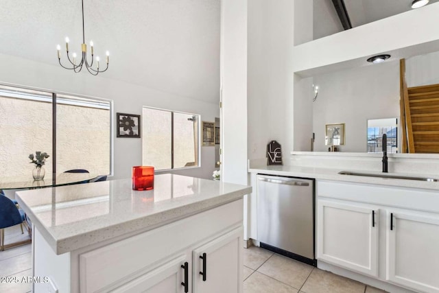 kitchen with a sink, white cabinetry, stainless steel dishwasher, light stone countertops, and decorative light fixtures