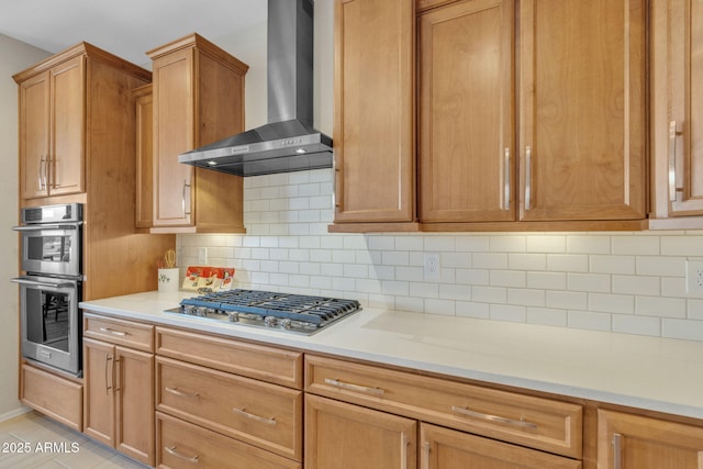 kitchen featuring wall chimney range hood, decorative backsplash, and appliances with stainless steel finishes