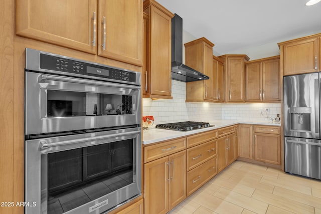 kitchen with tasteful backsplash, appliances with stainless steel finishes, and wall chimney range hood