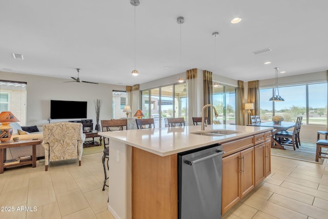 kitchen with pendant lighting, dishwasher, an island with sink, sink, and ceiling fan