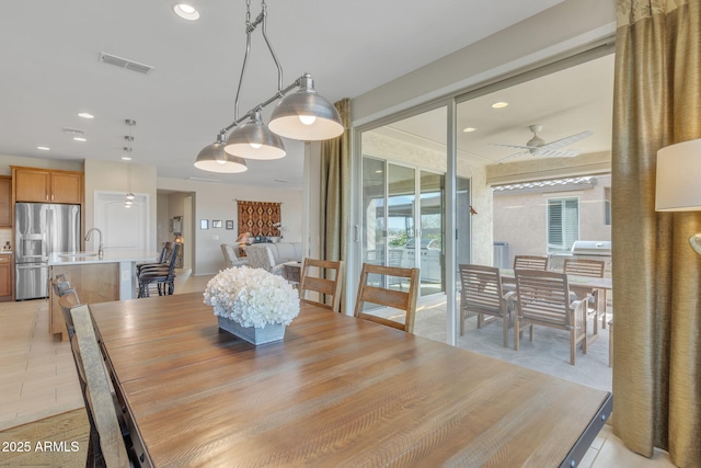 tiled dining space with ceiling fan and sink