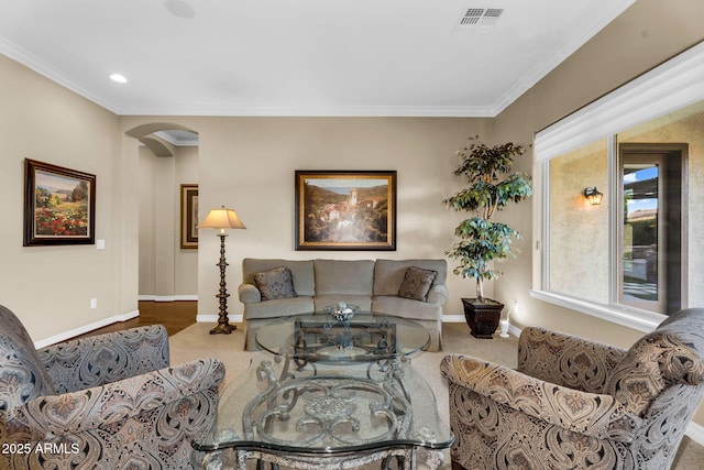 living area featuring arched walkways, visible vents, baseboards, and ornamental molding