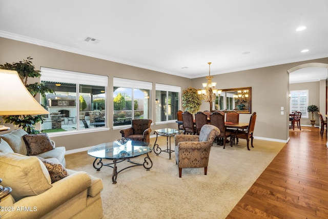 living room with baseboards, arched walkways, crown molding, and hardwood / wood-style flooring