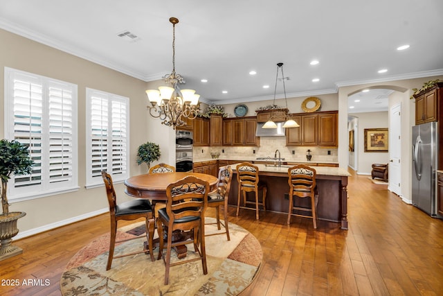 dining area featuring visible vents, arched walkways, crown molding, and hardwood / wood-style flooring