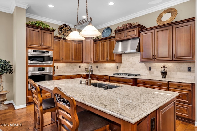 kitchen featuring under cabinet range hood, stainless steel appliances, ornamental molding, and a sink